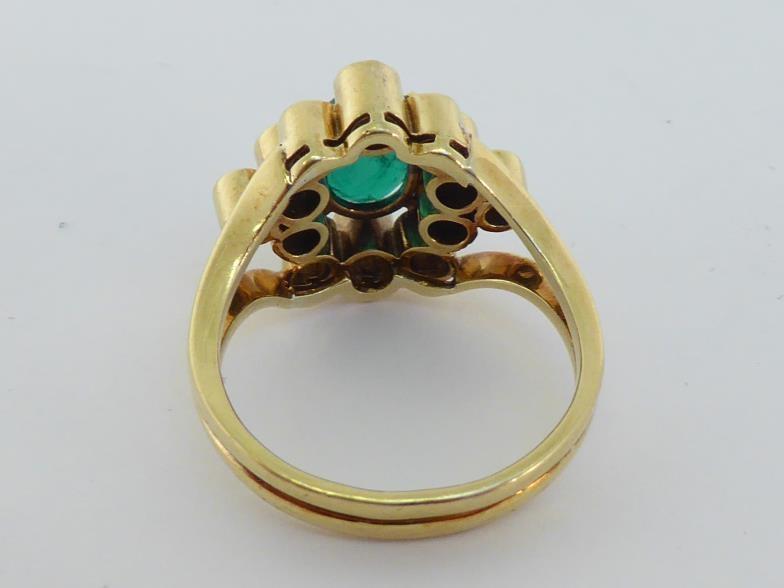 An emerald and diamond cluster ring, the central oval cut 8.4 x 6.6 x 3.2mm, in a surround of deep - Bild 3 aus 3