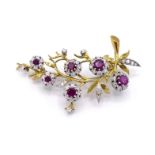 A ruby and diamond spray brooch, set with six graduating round cut ruby centred flowers, the largest