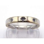 An 18 carat gold and diamond band, rub over set with three small brilliants, the shank fully
