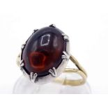 A brown tourmaline ring, the central oval cabochon 12.8 x 9.8mm, set in closed-back silver, the 18