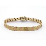 A two colour bracelet, composed of textured panel links, the box snap clasp stamped '14k', 19cm