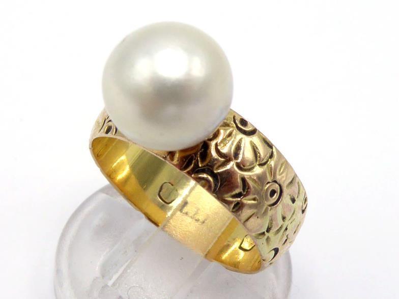 A gold and cultured pearl ring, the single round pearl 10.2mm diameter, to a floral chased band,