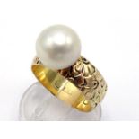 A gold and cultured pearl ring, the single round pearl 10.2mm diameter, to a floral chased band,