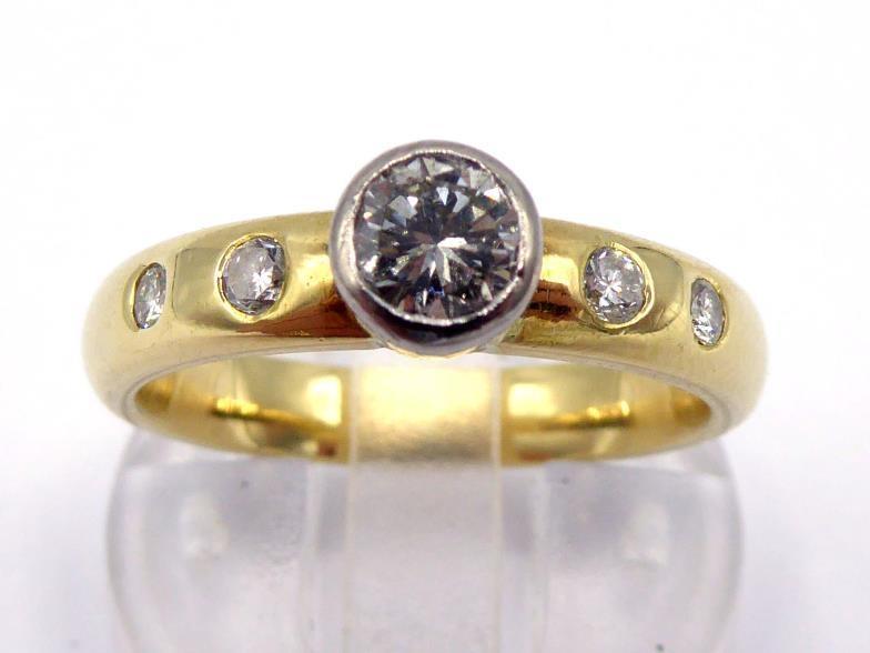 An 18 carat gold and diamond ring, the central brilliant approx. 0.28 carat, collet set above two