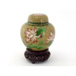 A Chinese cloisonné covered jar on wood stand, decorated with branches of flowers on yellow