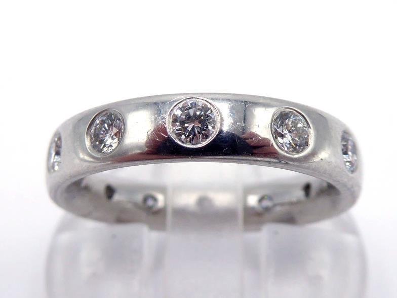 A platinum and diamond eternity band by Garrard & Co, the band rub over set at intervals with twelve