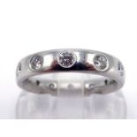 A platinum and diamond eternity band by Garrard & Co, the band rub over set at intervals with twelve