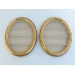 A pair of glazed gilt oval front opening wall display cases each containing three shelves . 35x45cm.