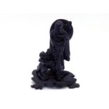 A Chinese carved black stone standing figure of an elderly swordsman on carved wood stand, with