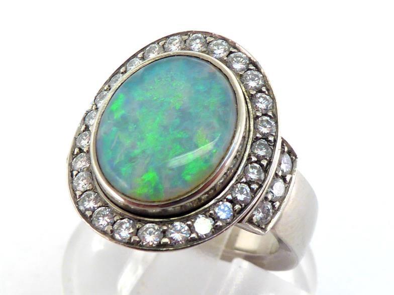 A precious opal and diamond cluster ring, the central oval opal cabochon 12 x 9.5mm, in a surround