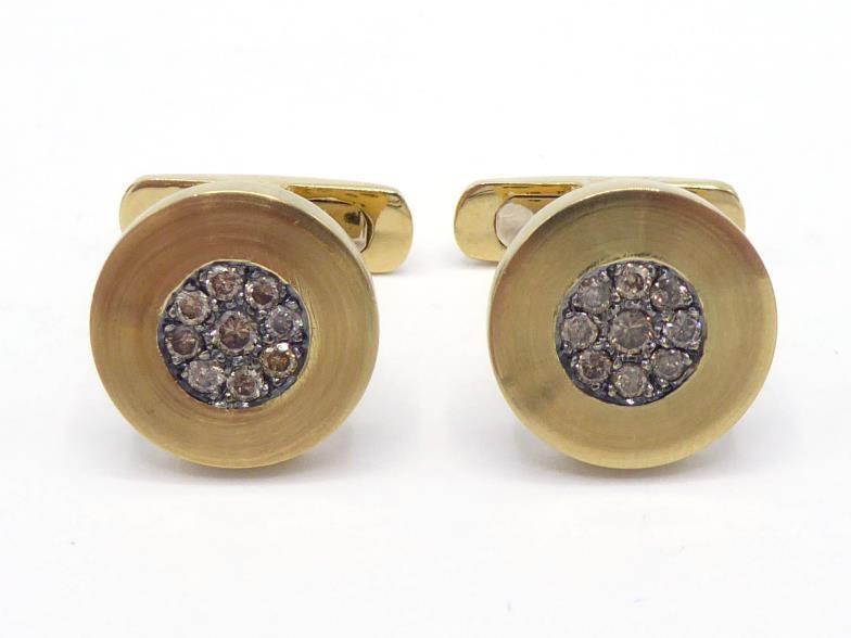 A pair of diamond cufflinks, the circular brushed gold links set to the centre with a cluster of