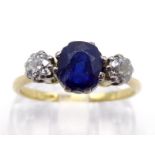 A sapphire and diamond three stone ring, the central oval cut stone 6 x 5mm, claw set between two