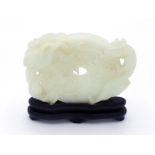 A Chinese carved white jade desk ornament of a Bi on hard wood stand, jade carved as bi form in