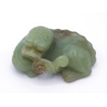 A Chinese carved yellow jade ornament of a recumbent Kylin, mouth holding a branch of Lingzhi, stone