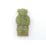 A Chinese carved yellow jade figure, in the form of a child holding a pigeon, wearing robe and