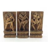 A group of three Indian carved wood erotic sculptures, each pair of lovers standing on a lotus base,