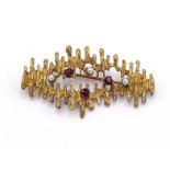 A 1970s yellow metal (tests 14 carat gold), garnet and seed pearl brooch, the textured openwork
