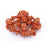 A mid 19th century carved coral brooch, designed as a group of four cherubs with roses in bloom