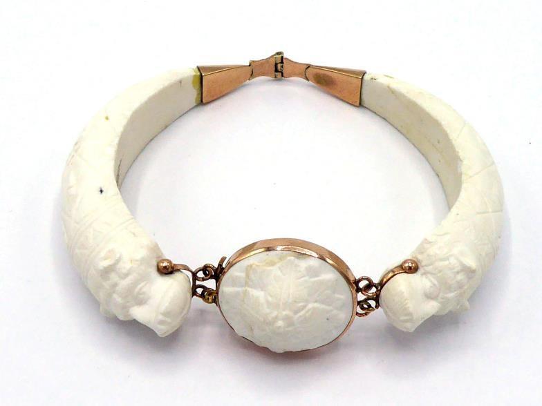 A 19th century carved white coral bangle, composed of two hinged sections terminating in a bear's