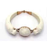 A 19th century carved white coral bangle, composed of two hinged sections terminating in a bear's