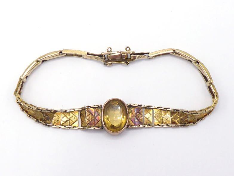 A 1940s citrine set yellow metal (tests 9 carat gold) bracelet, the central collet set oval cut