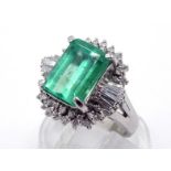 An emerald and diamond ballerina cluster ring, the central rectangular cut approx. 3.03 carats, in a