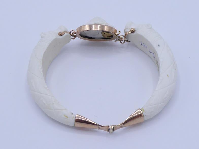 A 19th century carved white coral bangle, composed of two hinged sections terminating in a bear's - Image 2 of 3
