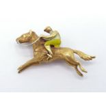 EQUESTRIAN INTEREST: an 18 carat gold and enamel brooch, modelled as a horse and rider, stamped '