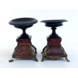 A pair of Boulle brass and faux red tortoiseshell panelled shaped square ebonised stands with ormolu