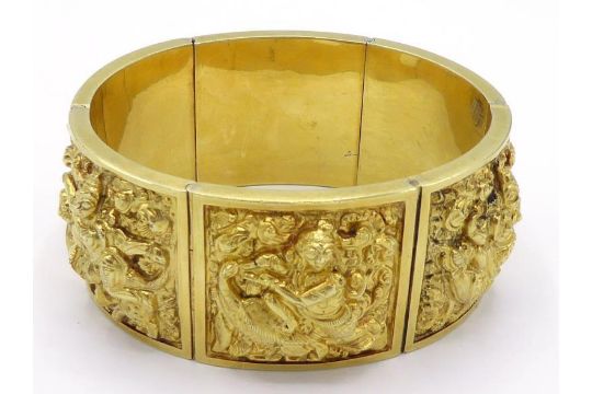 An Indian yellow metal (tests 14 carat gold) bangle, each link embossed with a Buddhist deity, to - Image 1 of 5