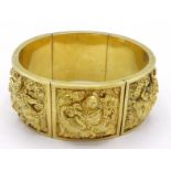 An Indian yellow metal (tests 14 carat gold) bangle, each link embossed with a Buddhist deity, to