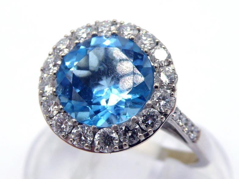 An 18 carat white gold, blue topaz and diamond cluster ring, the central round cut stone 8 x 4.