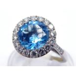 An 18 carat white gold, blue topaz and diamond cluster ring, the central round cut stone 8 x 4.