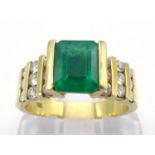 An emerald and diamond ring, the central emerald cut emerald 7.9 x 6.1 x 4mm, to channel set