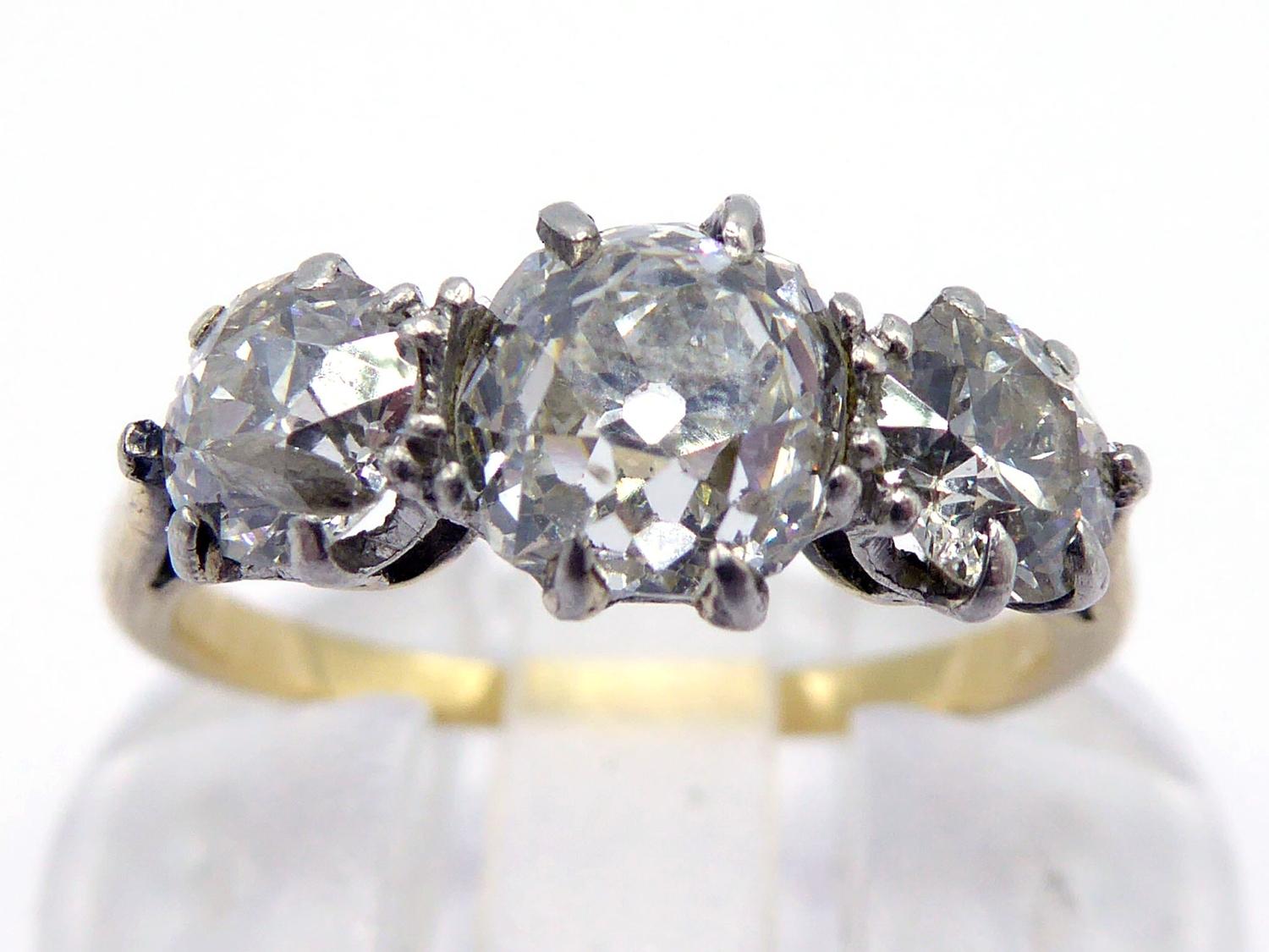 A three stone diamond ring, the central old mine cut approx. 0.75 carat, flanked by two old