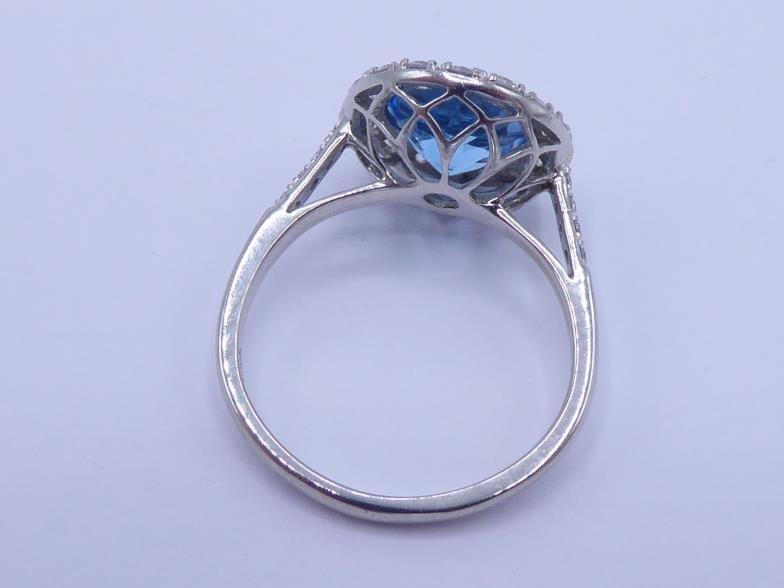 An 18 carat white gold, blue topaz and diamond cluster ring, the central round cut stone 8 x 4. - Image 4 of 5
