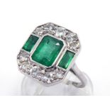 An emerald and diamond plaque ring, the central emerald cut emerald 8 x 6 x 4.4mm, two smaller