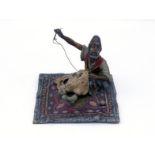 A cold painted Austrian bronze of a bearded Arab leather worker sewing a skin, seated on a carpet.