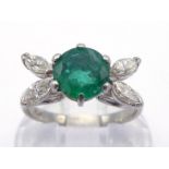 An emerald and diamond ring, the central round cut stone 7 x 4.2mm, with a pair of marquise cut