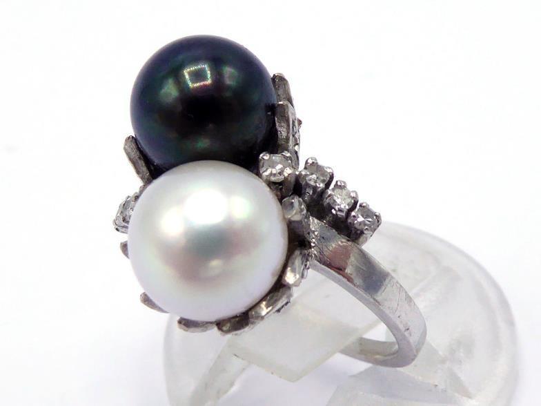 A two colour pearl and diamond ring, the cross over mount with an 8.2mm black and white pearl, a