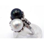 A two colour pearl and diamond ring, the cross over mount with an 8.2mm black and white pearl, a