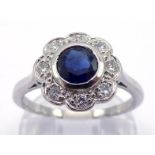 A platinum, sapphire and diamond daisy cluster ring, the central round cut sapphire 5 x 2.8mm, in