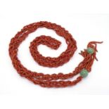 A 20th century Chinese coral and jadeite robe cord, composed of four strands of braided coral, to