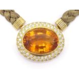 An 18 carat gold, citrine and diamond pendant, the large oval cut citrine 30 x 22 x 15mm, in a