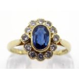 An 18 carat gold, sapphire and diamond cluster ring, the central oval cut sapphire 4 x 6 x 2.4mm, in