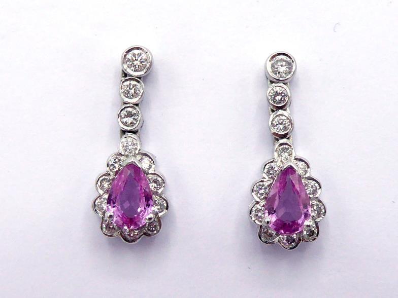 A pair of pink sapphire and diamond earrings, the central pear cut sapphire drop in a surround of