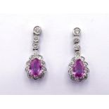 A pair of pink sapphire and diamond earrings, the central pear cut sapphire drop in a surround of