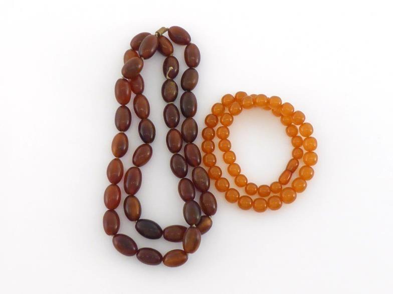 An amber bead necklace, composed of uniform oval beads, each 20.8mm long, to a screw barrel clasp,