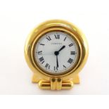 CARTIER, a gilt metal bedside clock, the circular case with white dial, black Roman numerals, and