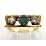 An emerald and diamond ring, the central oval cut emerald flanked by two brilliants, totalling